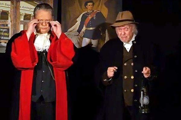 Der Richter nimmt die Brille ab, daneben ein Mann mit Laterne